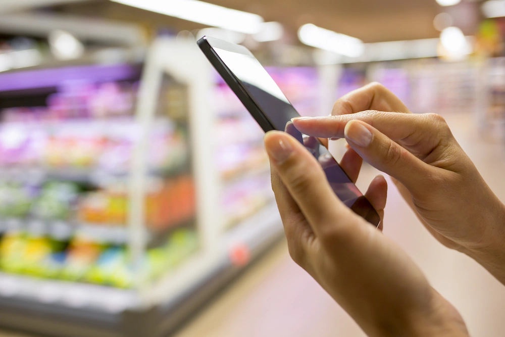 A woman using her smartphone to buy groceries while in-store